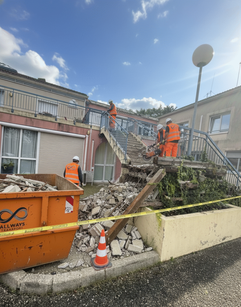 Équipe Allways Transport réalisant la démolition d’un escalier en béton avec benne à gravats sur chantier.